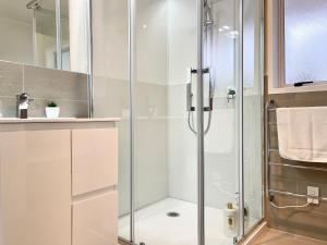 a shower with a glass door in a bathroom at Quiet, private and 5-bedroom holiday house in Hamilton +40 photos