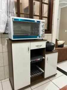 a microwave sitting on top of a cabinet in a kitchen at Vista Mar em PIÚMA in Itapitanga