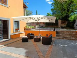 une terrasse avec un parasol, des canapés et des chaises dans l'établissement Casale la Quercia - Splendido casale nella natura, à Cura