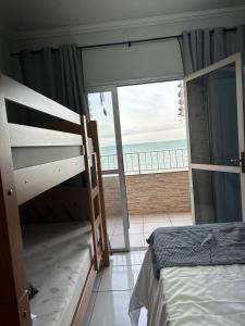 a bedroom with a bunk bed and a view of the ocean at Vista Mar em PIÚMA in Itapitanga