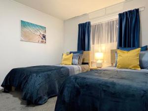 two beds in a room with blue and yellow pillows at Quiet, private and 5-bedroom holiday house in Hamilton