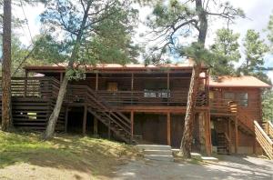 a large wooden house with stairs in the woods at Bearadise in Ruidoso
