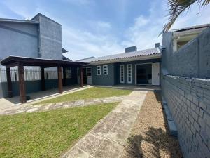 ein Haus mit einem Hof neben einem Gebäude in der Unterkunft Casa Espaçosa e Confortável para Aluguel de Verão in Capão da Canoa