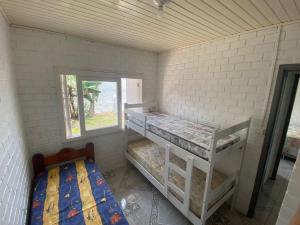 ein Zimmer mit zwei Etagenbetten und einem Fenster in der Unterkunft Casa Espaçosa e Confortável para Aluguel de Verão in Capão da Canoa