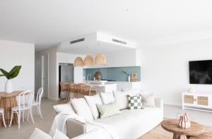 a white living room with a white couch and a kitchen at Magenta Palms in Magenta