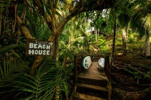 a wooden boardwalk in a forest with a beach house sign at Bocas Sunset Beach House in Bocas del Toro