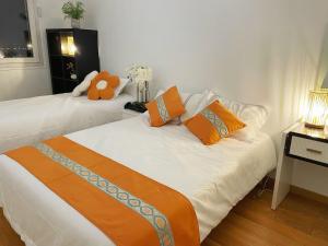 1 Schlafzimmer mit 2 Betten mit orangefarbenen Kissen und einem Teddybär in der Unterkunft Appartement de 4pieces Gennevilliers in Gennevilliers