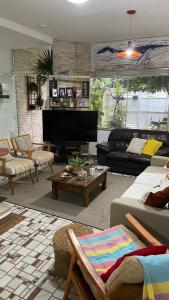 ein Wohnzimmer mit Sofas und Fernseher in der Unterkunft Suite Casal Mar e Lua em casa compartilhada in Ubatuba