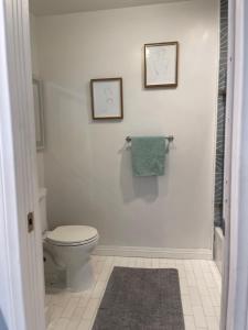 a bathroom with a toilet and two pictures on the wall at Studio Stay in West Covina