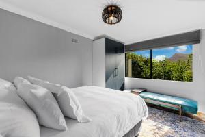 une chambre avec un lit blanc et une grande fenêtre dans l'établissement Zuri's Cottage Houtbay, à Hout Bay 48 autres photos