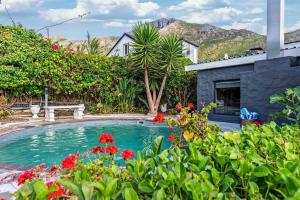 une piscine dans une cour fleurie dans l'établissement Zuri's Cottage Houtbay, à Hout Bay