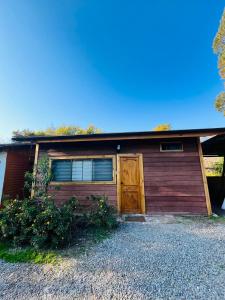 a red house with a garage with a door at Cabañitas Remanso del Espíritu in Isla de Maipo