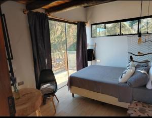 a bedroom with a bed and a large window at Prana Cabaña Kira 3 hab in Samaipata