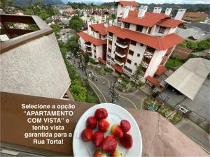 a plate of strawberries on a table with a view of a city at Pousada do Serrano - Rua Torta in Gramado +11 photos