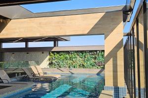 a swimming pool with two chairs next to a house at Loft Elegante Centro in Dourados