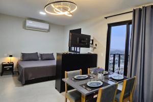 a room with a bed and a table with a dining room at Loft Elegante Centro in Dourados