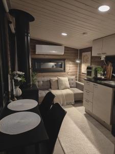 アカスロンポロにあるLapland Riverside Cabin 4 HILLA , Ylläs, Tiny Home with Sauna, Fireplace, Terrace, BBQ, Wifi, Ski, Fishing, Pets OKのソファとテーブルのあるリビングルーム