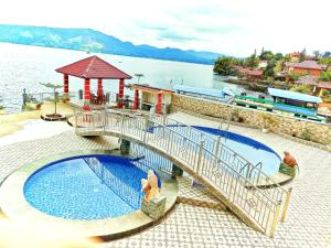 un puente sobre una piscina al lado de un cuerpo de agua en Judita Cottages, en Tuk Tuk