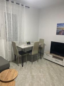 a living room with a table and chairs and a television at Apartment Jon 1 in Vlorë +2 photos