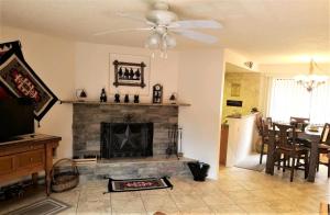 a living room with a fireplace and a ceiling fan at Pinecliff Retreat in Ruidoso