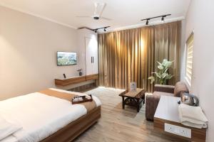a bedroom with a bed and a living room with a couch at Rumuk Boutique Resort - Offbeat escape in Dhanaulti