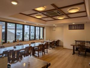 a dining room with tables and chairs and windows at Oyado Nozawaya in Nozawa Onsen