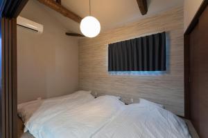 a bedroom with a white bed with a window at 鱗町庵 in Kanazawa