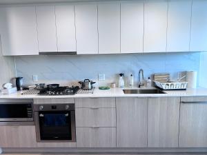 a kitchen with white cabinets and a stove and a sink at New condo near Lougheed Mall & SFU in Coquitlam