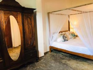 a bedroom with a canopy bed and a mirror at Coastal Cloud Backpackers in Unawatuna