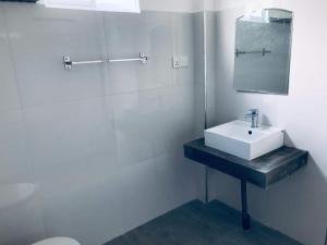 a white bathroom with a sink and a mirror at Coastal Cloud Backpackers in Unawatuna