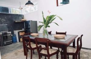 a dining room table with chairs and a vase with a plant at Coastal Cloud Backpackers in Unawatuna