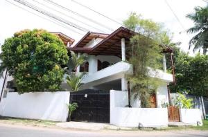 a house with a fence in front of it at Coastal Cloud Backpackers in Unawatuna