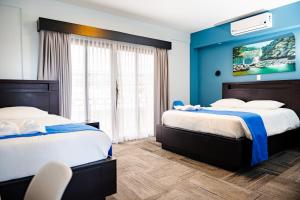 two beds in a room with blue walls at Hotel Luckys in San Isidro de El General