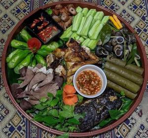 a plate of food with meat and vegetables on a table at Sweet Mai Châu Homestay in Hòa Bình