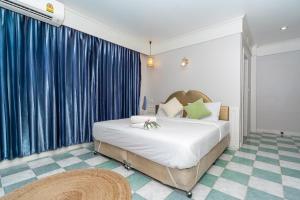 a bedroom with a large bed with blue curtains at Patong Social Hotel & Restaurant, Patong Beach in Patong Beach