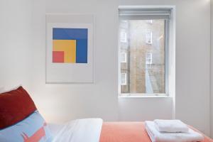 a bedroom with a bed and a window at Fitzrovia Apartment By Morethanstays in London