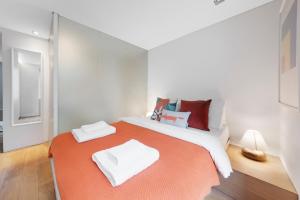 a bedroom with a large bed with an orange blanket at Fitzrovia Apartment By Morethanstays in London