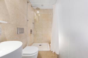 a white bathroom with a toilet and a shower at Fitzrovia Apartment By Morethanstays in London