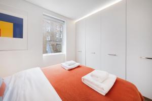 a bedroom with a bed with two towels on it at Fitzrovia Apartment By Morethanstays in London