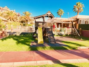 a playground in front of a house with palm trees at Alcaudón, Isla Canela - By AC REAL in Isla Canela