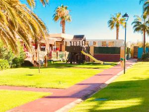 a house with a playground in a yard with palm trees at Alcaudón, Isla Canela - By AC REAL in Isla Canela