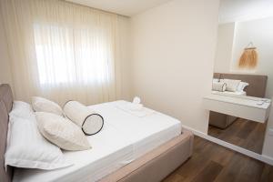 a bedroom with a bed with white pillows and a sink at iunn apartment 2 in Vlorë