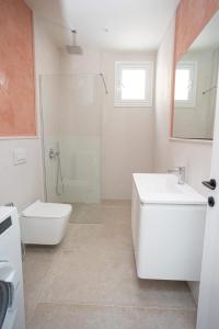 a white bathroom with a sink and a shower at iunn apartment 2 in Vlorë +7 photos