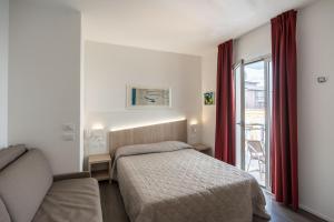 a bedroom with a bed and a couch and a window at Hotel Marzia Holiday Queen in Caorle +43 photos