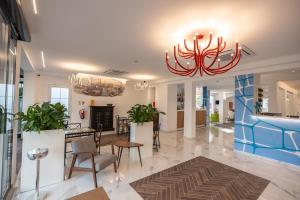 a lobby with a chandelier and tables and chairs at Hotel Marzia Holiday Queen in Caorle