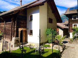 una piccola casa bianca con sedie di fronte di LA CÀ NOVA. South Switzerland cozy gate away. a Osco