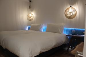a bedroom with a large white bed with two lights at RIOSHOUSE Henley in Henley on Thames