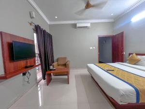 a bedroom with a bed and a tv and a chair at Hotel Gateway Suites Bangalore Airport in Bangalore