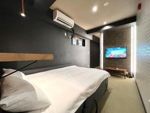 une chambre avec un lit et une télévision à écran plat dans l'établissement Asakusa-Smile, à Tokyo