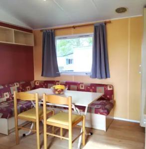 ein Esszimmer mit Tisch und Stühlen und einer Couch in der Unterkunft Mobilhome 5 place proche mer in Angles